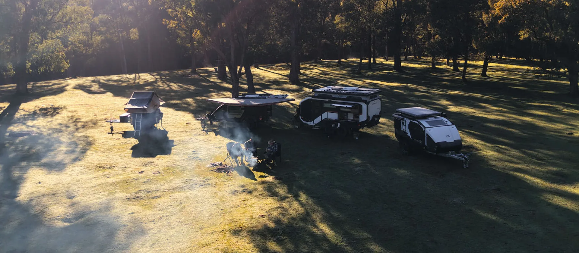 Stockman Rover, Trekka and Pod Trailers parked around a campfire in a forest clearing
